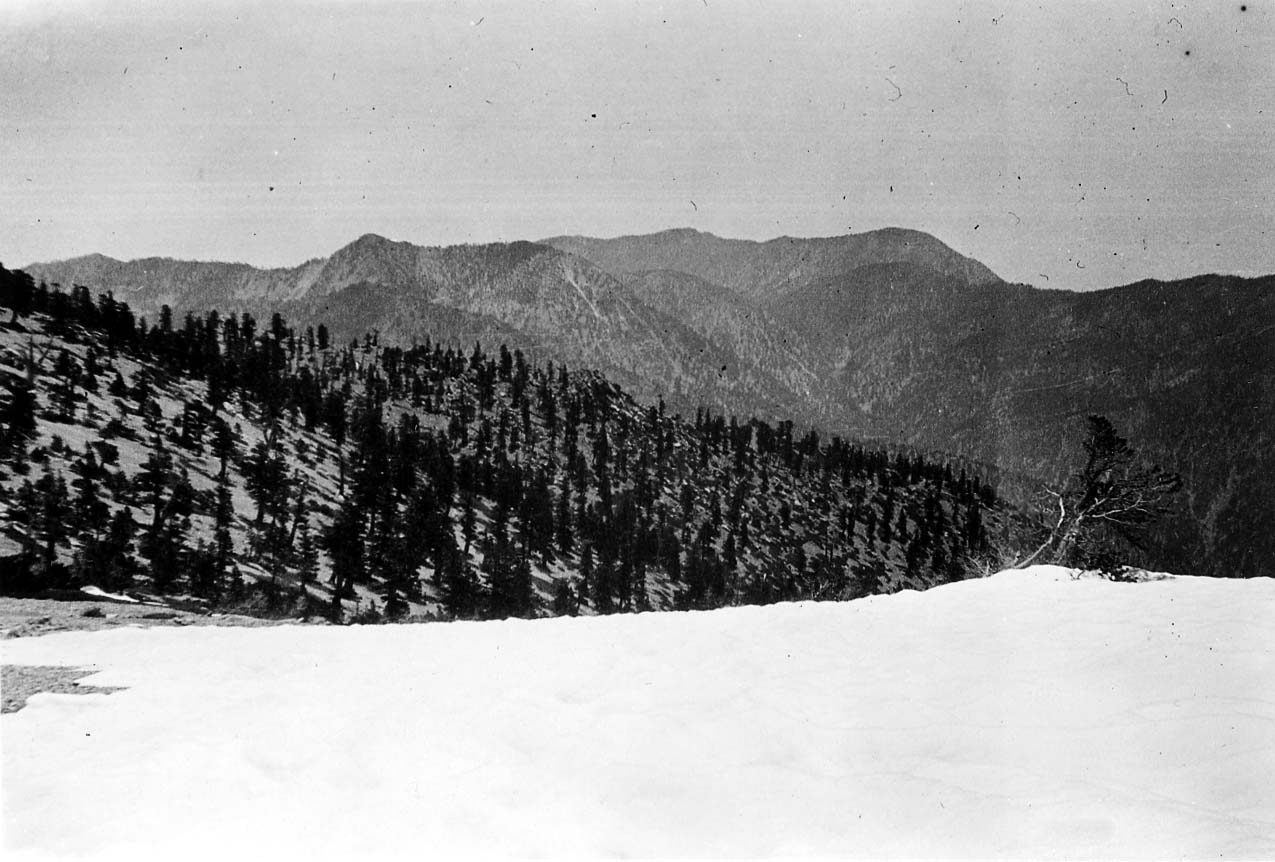 Low-hanging clouds settling into a deep mountain valley with show framing the cold ground.