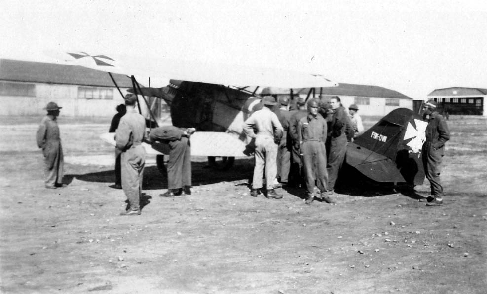 Army Air Corps flight cadets, including Donald A. Hall Sr. wearing a flight cap, examining a captured German WWI biplane with Iron Cross markings at Brooks Field.
