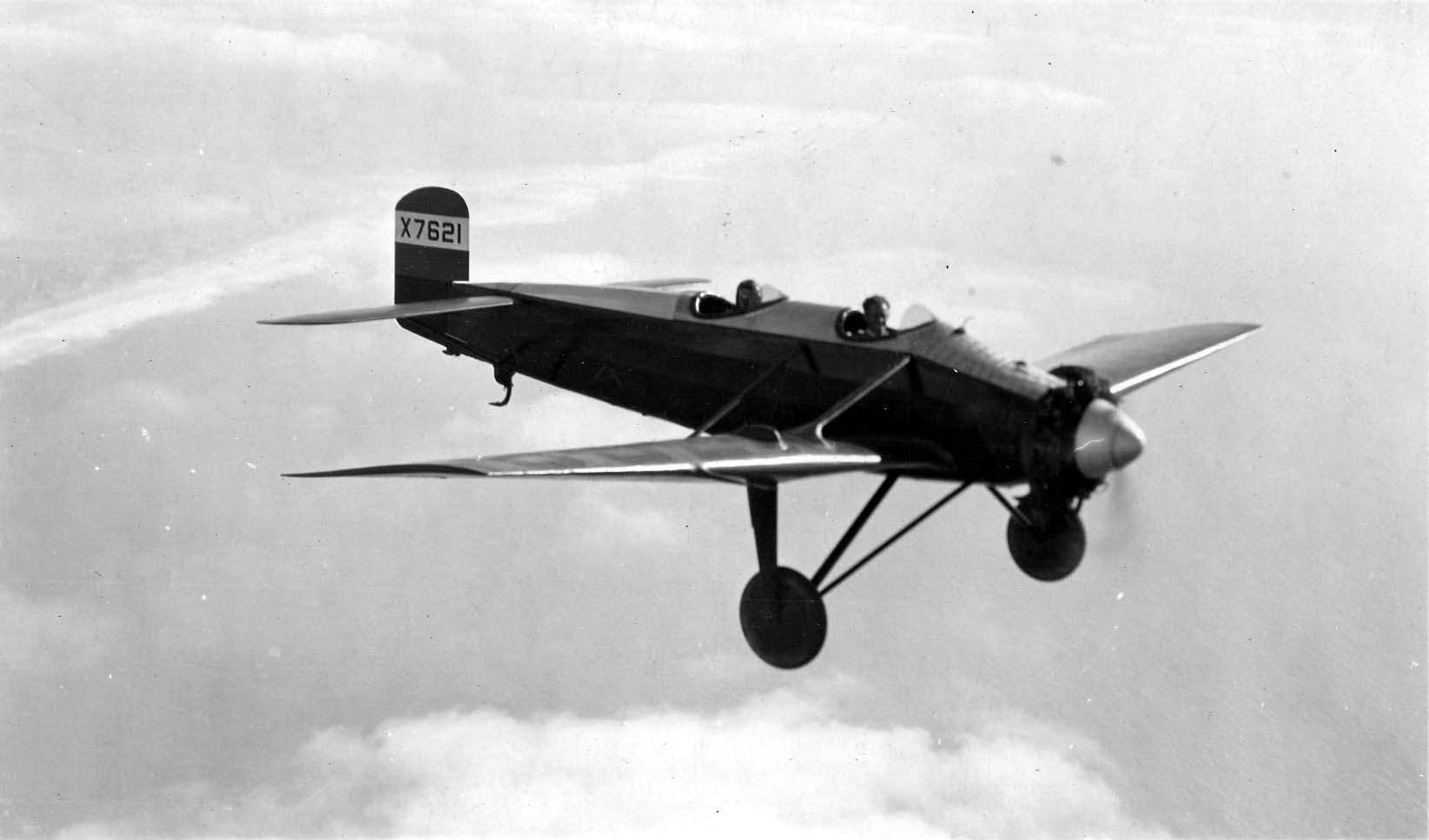 An air-to-air photograph of the Hall X-1 prototype X7621 banking in high-altitude flight above the coastal marine layer and Pacific Ocean.