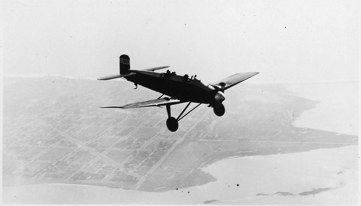 An air-to-air high-angle view of the Hall X-1 prototype X7621 banking high above the urban grid of San Diego and coastal bay.