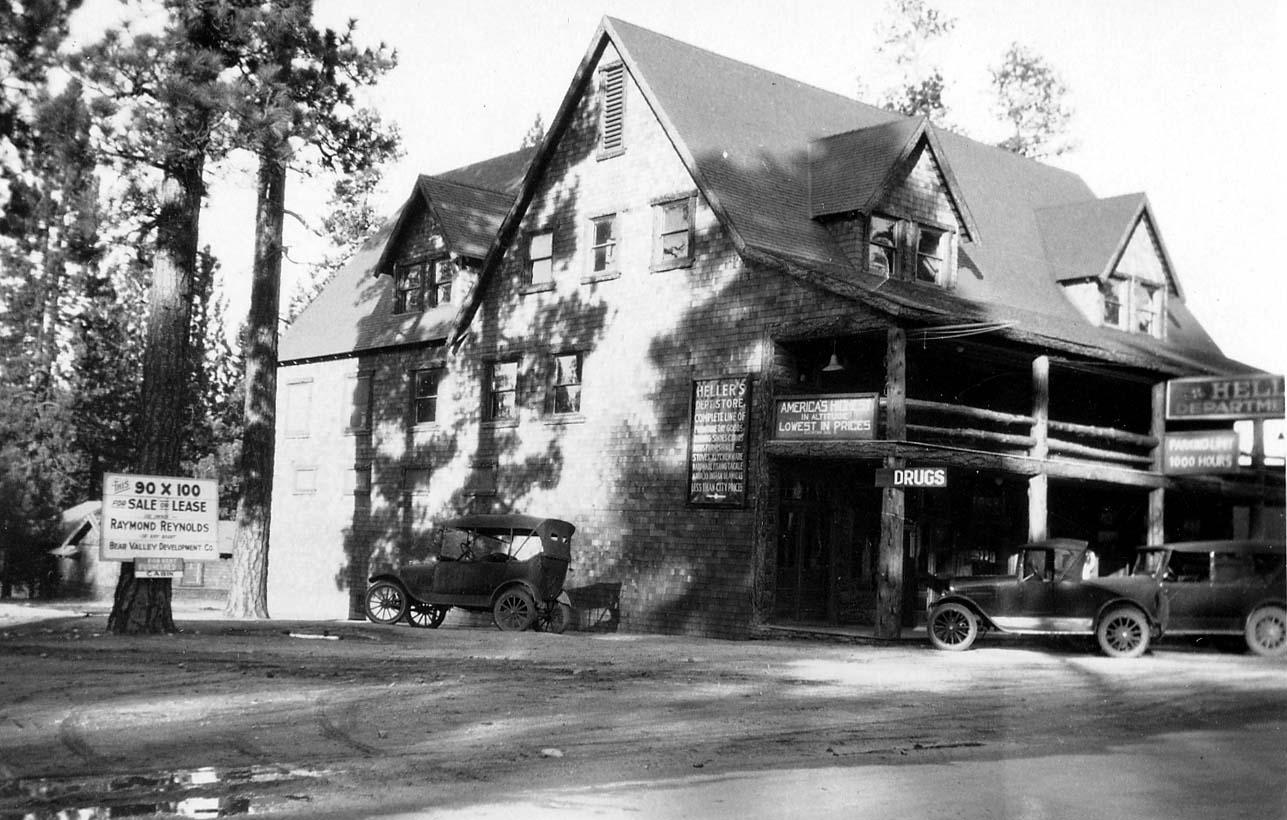 The multi-story rustic wooden and stone facade of Heller's Department Store in Big Bear Lake with vintage cars parked out front.