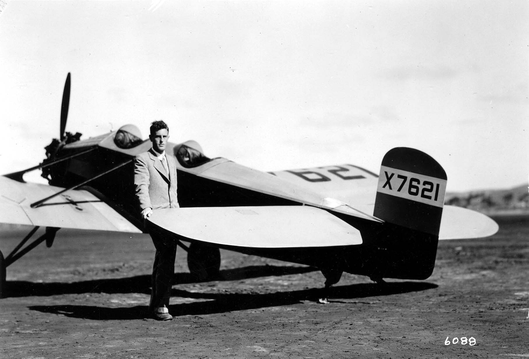 Donald A. Hall standing beside the tail of his proprietary low-wing monoplane X7621 on an airfield.
