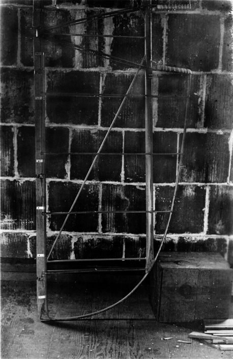 The bare tubular steel framework of the Spirit of St. Louis horizontal tail surface resting against a brick wall.