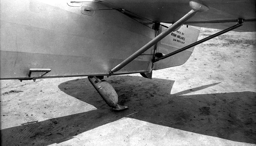 Ground-level detail photograph of the aft fuselage underside showing tail skid shoe and horizontal stabilizer struts.