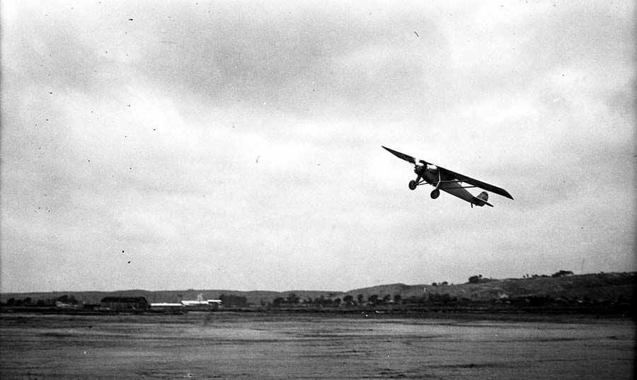 Low-angle action photograph of the Spirit of St. Louis climbing into the overcast sky over Dutch Flats.