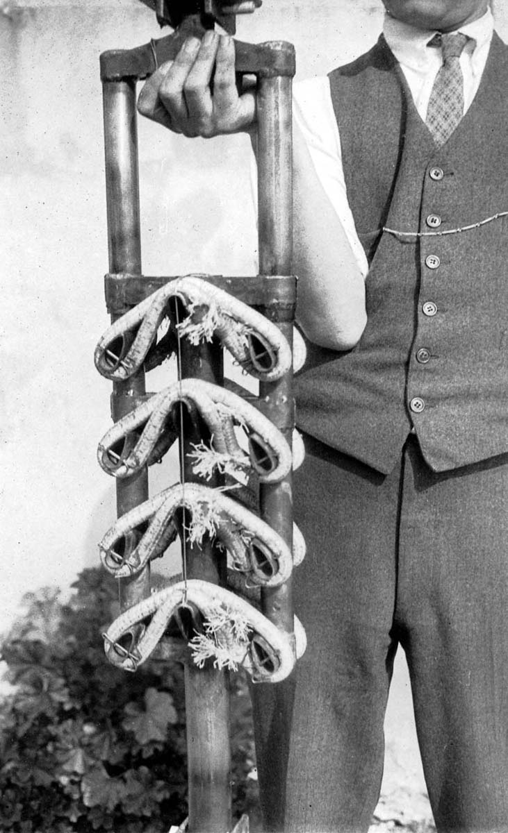 Close-up of bare telescoping landing gear shock strut showing four industrial bungee cord loops held by shop technician.