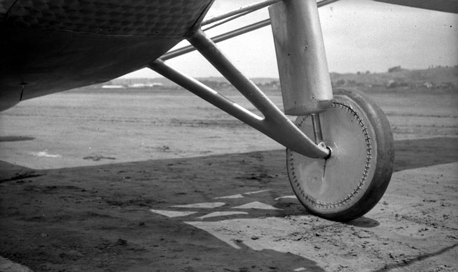 Macro ground-level photograph of the right landing wheel showing fabric disc stitching and streamlined shock strut boot.