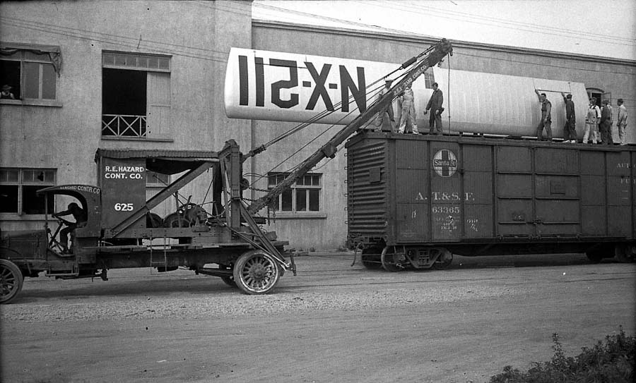 Broad side view of R.E. Hazard crane truck 625 lifting the 46-foot Spirit of St. Louis wing beside a railroad boxcar.