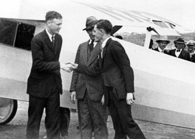 Vintage photo in 1927 with pilot Charles Lindbergh and Chief engineer Donald Hall shaking hands in front of the Spirit of St. Louis in San Diego, California. Owner Frank Mahoney is behind them.