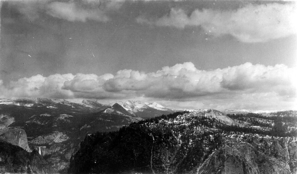 Vintage black and white landscape photograph from high above Yosemite valley. The distant mountains are obscured by clouds. Taken at Yosemite National Monument, California by aircraft engineer Donald Hall.