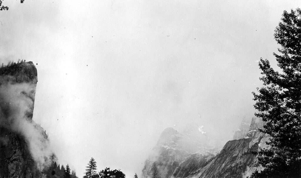 Vintage black and white photograph looking into the snowy mists of the valley. Taken at Yosemite National Monument, California by Donald Hall.