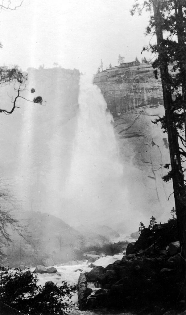 Vintage black and white photograph looking up from the bottom of a waterfall collecting in a rocky creek. Taken at Yosemite National Monument, California by Donald Hall.