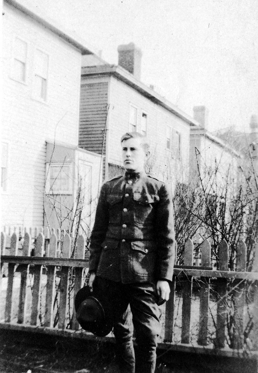 A vintage black and white photograph of a young Donald A. Hall dressed in his WWI soldier uniform in the backyard of the Hall family home in Brooklyn, New York in 1917 or 1918 while he was attending the Pratt Institute of Technology.