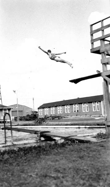 Vintage Black and White photograph of male diver captured in mid-air as he flies above a pool. Photo taken by Donald Hall in 1925 at Brooks Field Army base in Texas.
