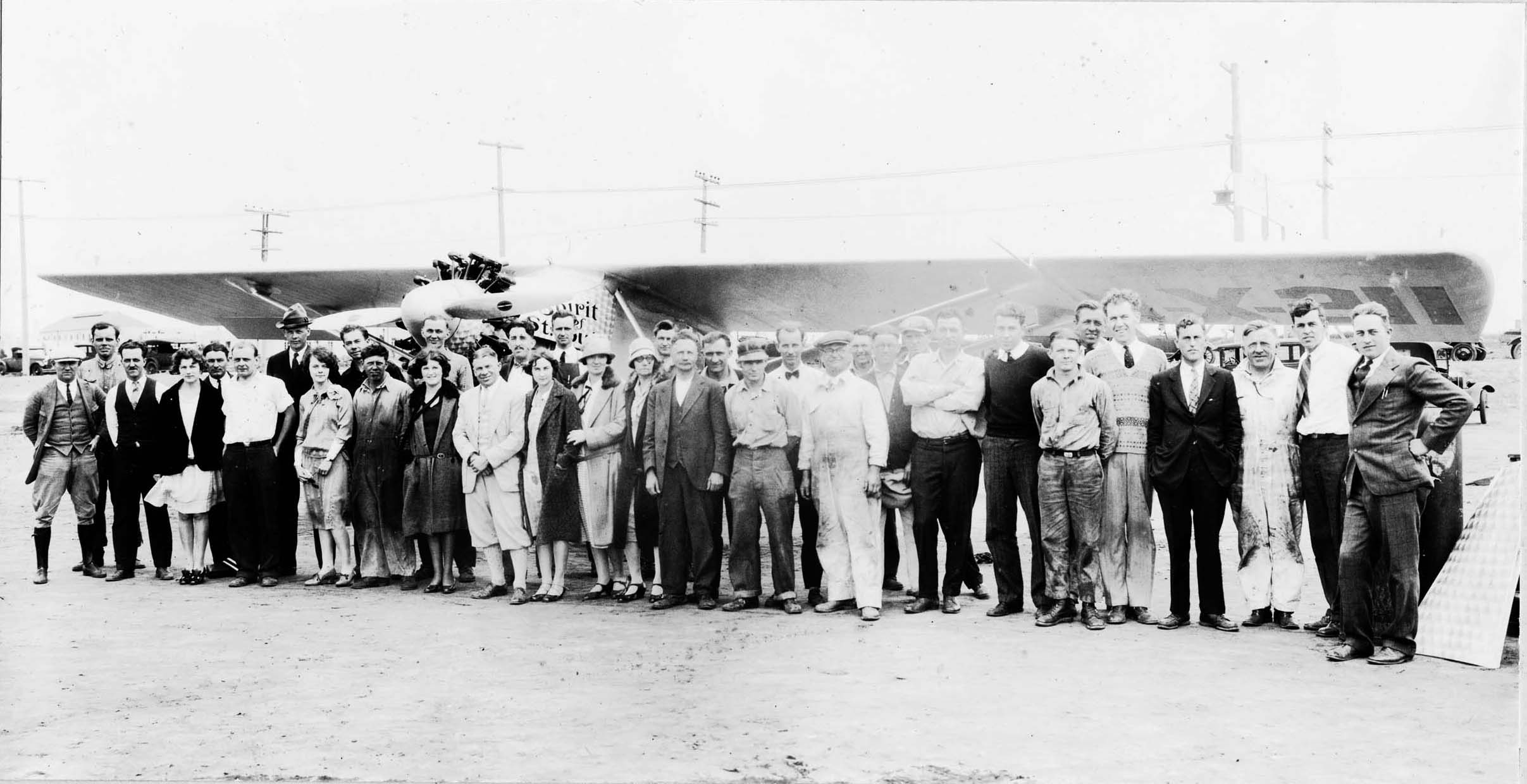 A vintage black and white team photograph of the Spirit of St. Louis with the majority of the work crew that assembled the plane at Ryan Airlines in San Diego, California May 1927. Including pilot Charles Lindbergh, designer Donald Hall, owner Ben Mahoney, AJ Edwards, and production manager Hawley Bowlus.