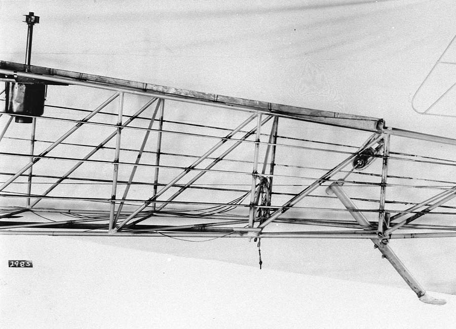 A vintage black and white photograph of the Spirit of St. Louis airplane's internal tail section. Visible is the wind powered generator for the Earth Inductor compass, the internal acuated cables, and the elastic band shock absorber for the tail dragging skid. This image is before it is covered in silver cloth. This was photo was included in the Technical Notes number 257 which was presented to National Advisory Committee for Aeronautics in 1927 by its Chief Engineer, Donald A. Hall.