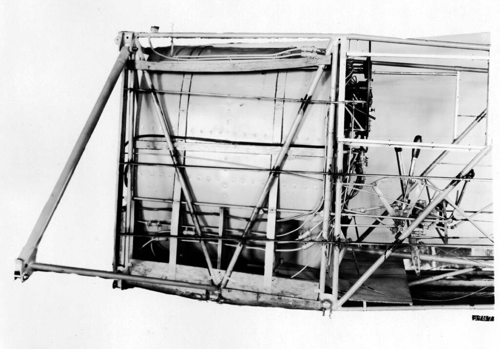 A vintage black and white edited photograph of the Spirit of St. Louis airplane. You can see the main fuel tank and cockpit with all controls installed,  before it is covered in silver cloth. The image shows the plane while still being assembled and is included in the Technical Notes No. 257 which was presented to National Advisory Committee for Aeronautics in 1927 by its Chief Engineer, Donald A. Hall.