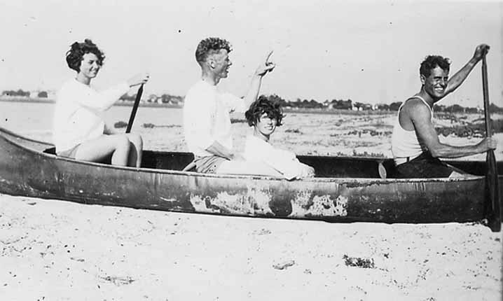 Funny vintage selfie photo of Donald Hall smiling at the camera with two young ladies. The four are sitting in a canoe while on the beach in San Diego, California. One of a series of photos by the engineer of the Spirit of St. Louis.