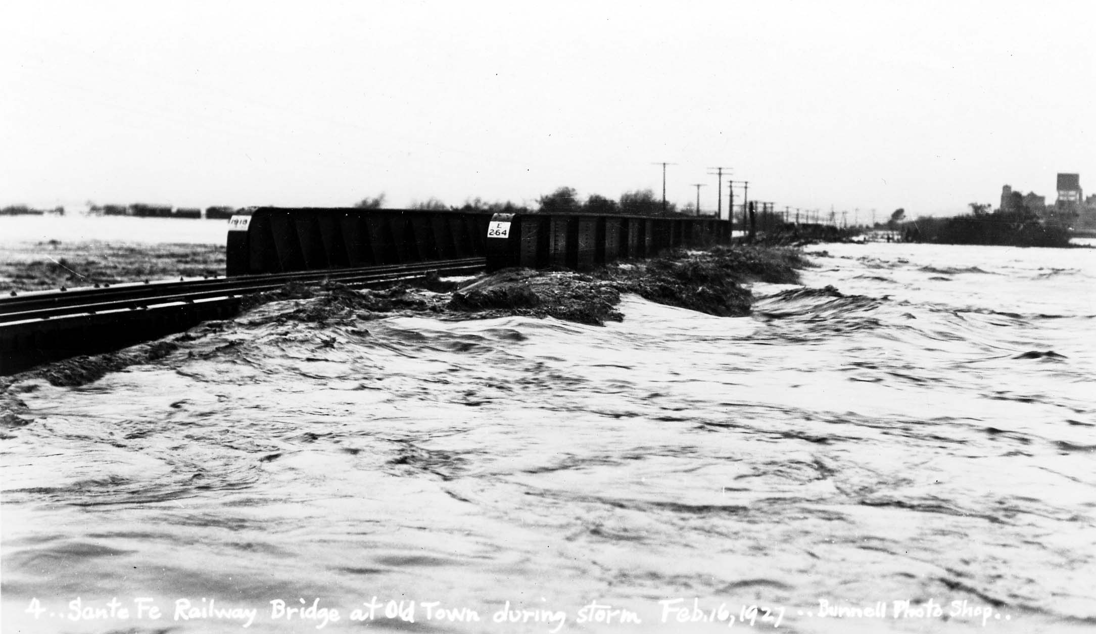 A vintage black and white photograph of flooding in San Diego, California on February, 16th 1927 before the city built flood controls to prevent the airfield and parts of the city from being submerged. This is why young pilot Charles Lindbergh had to reach the the city via an alternative route.