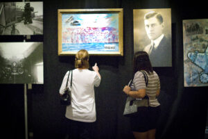 Women attending the Flying Over Time exhibition at ASU with Nova Hall's paintings, Donald Hall's portrait, photography in 2011